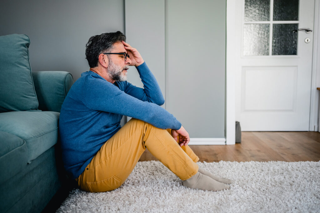 Man sitting on the floor, hand on forehead — reflecting on intimacy, frustration, or emotional overwhelm