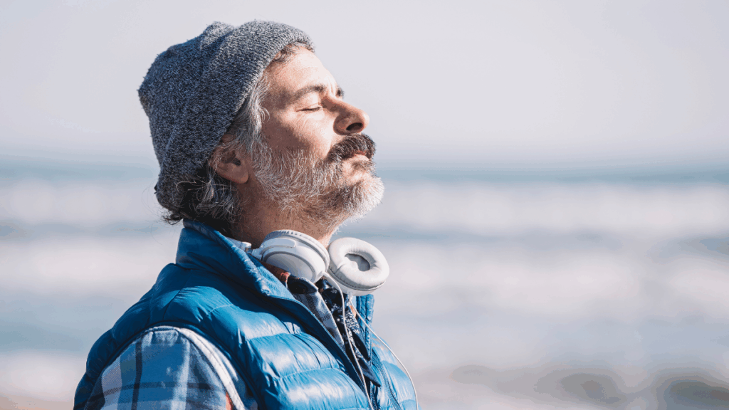 Man taking a deep breath peacefully at the beach, symbolizing release of performance pressure and unshaming.