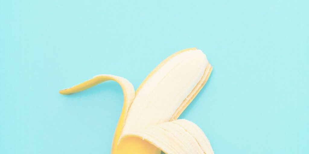 Partially peeled banana on blue background representing circumcision and foreskin health.