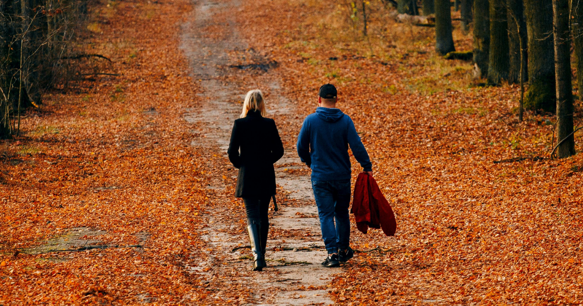 A couple walking together through an autumn path, representing connection, support, and navigating early ejaculation as a team.